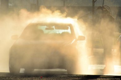 car in steamy hand car wash backlit by sun