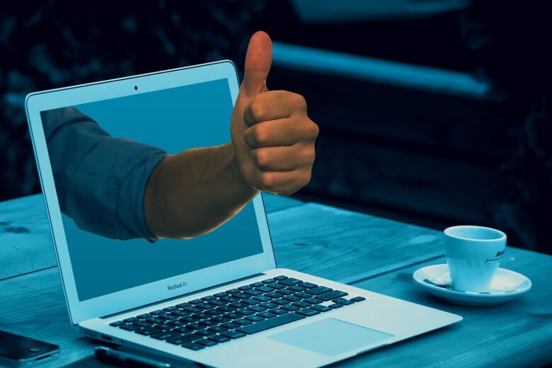 hand and thumbs up reaching through laptop screen