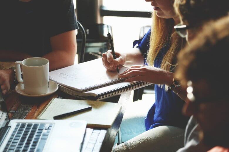 People sitting around a table working with laptop and making notes