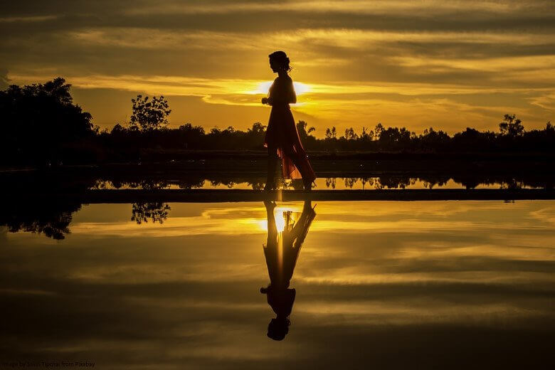 Woman walking at a beach in the sunset