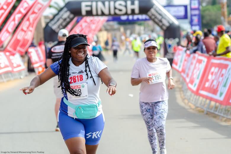 Woman crossing the finishing line at a marathon looking very happy