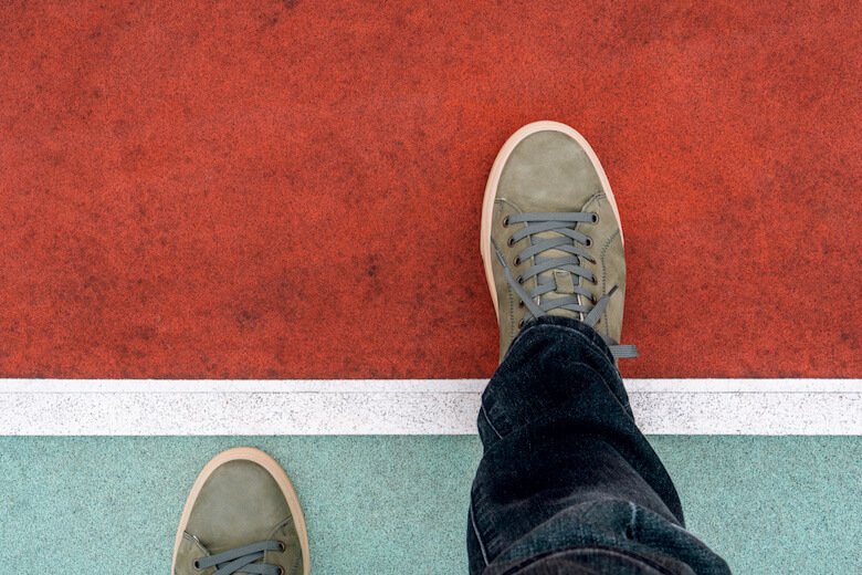 Man stepping over a white line. Walking across the start line representing business and life start up concept. Top view.