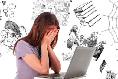 frustrated woman sitting at laptop with head in hands