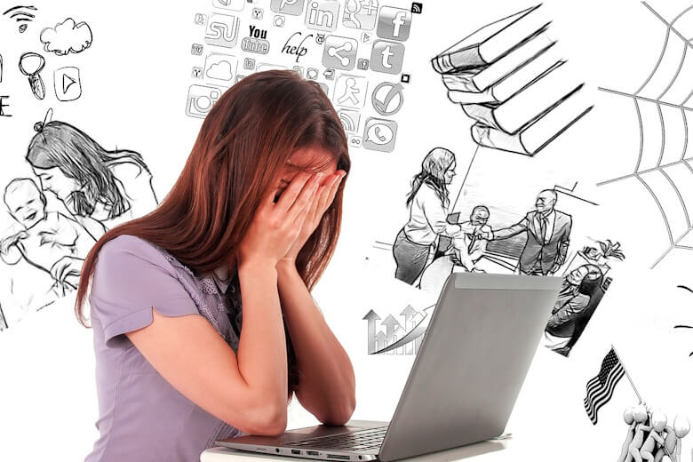 frustrated woman sitting at laptop with head in hands