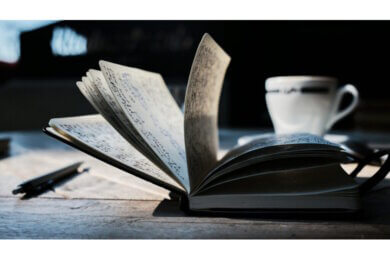 pages of an open book fanned and a cup