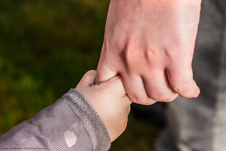 Child's hand holding on to a man's hand