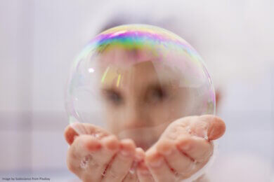 Hands holding a bubble and a face behind it